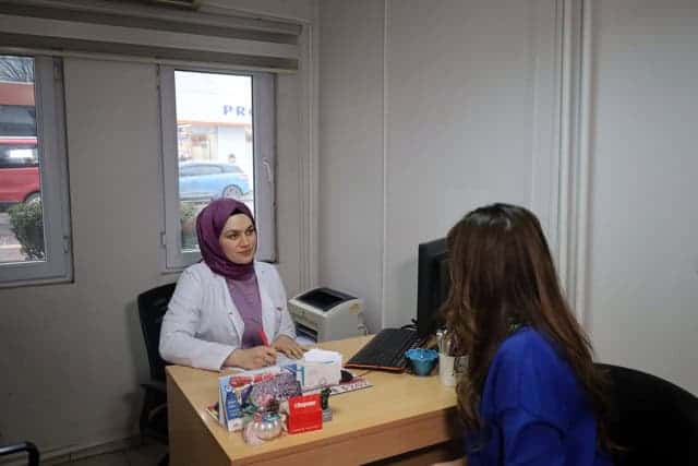 Basın merkezinde görüşen iki kişi, profesyonel ortamda iletişim kuruyor.